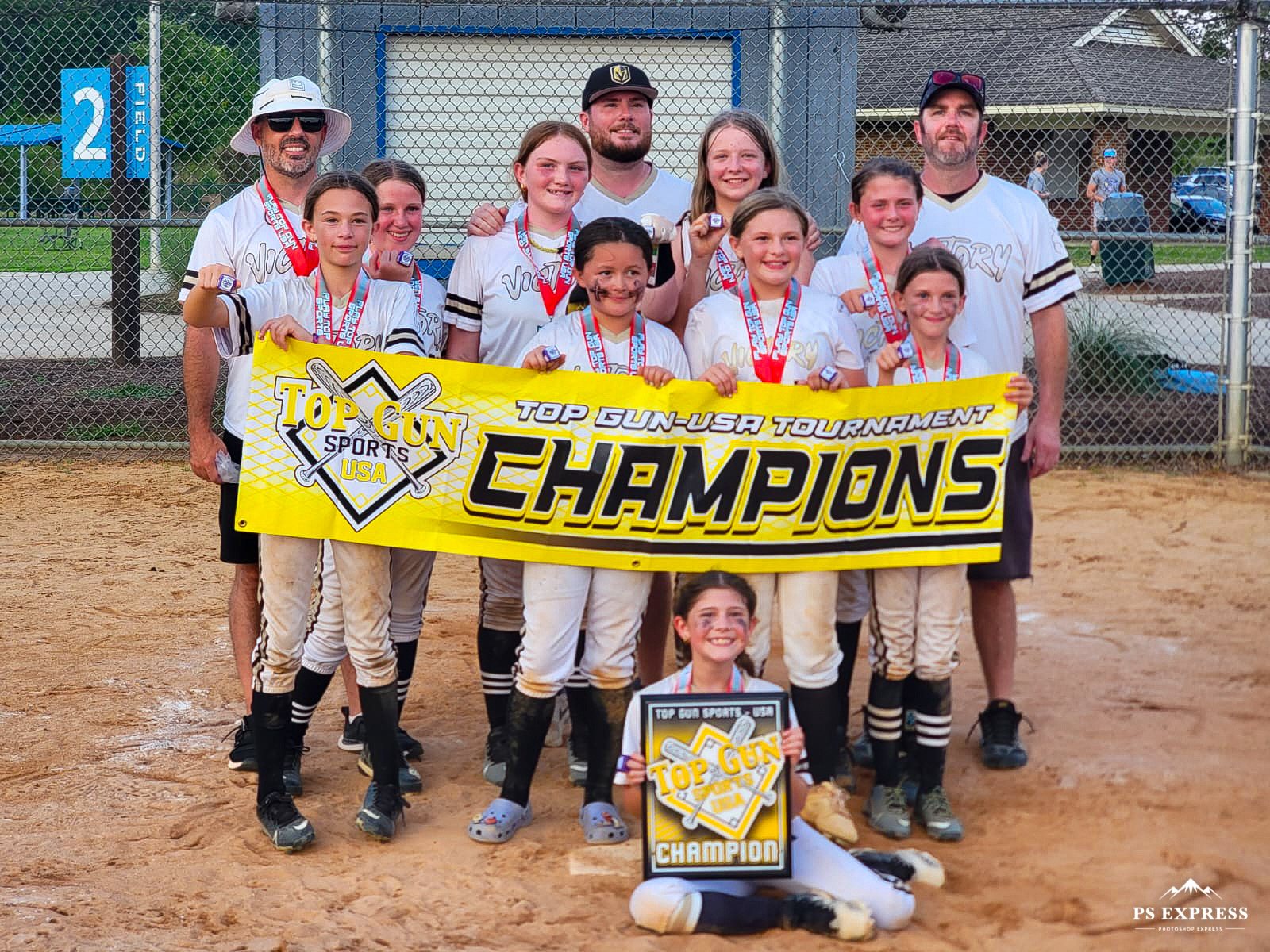 Softball team and coaches proudly holding a Top Gun Tournament Champions banner and plaque.
